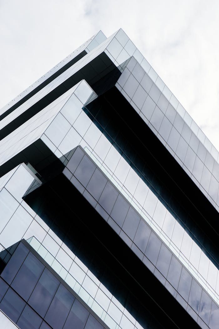 about-us Low angle view of a modern glass skyscraper with sleek geometric lines and reflections.