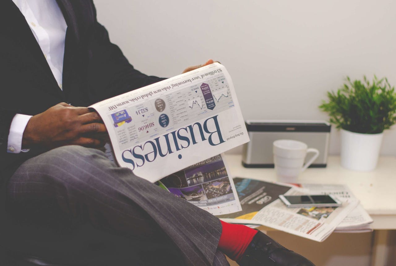 embark Businessman reading a financial newspaper at a desk, highlighting finance and commerce theme.